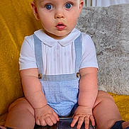Woody joined the competition — help win amazing prizes! baby, child, blue_eyes, blue_shoes, white_shirt, blue_overalls, smartphone, yellow_blanket, indoor, curious, sitting, plush_cushion, home, portrait, cute, hands, legs, fashion, technology, expression