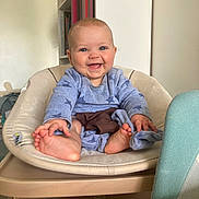 Gaïane participe au concours pour gagner de l'argent avec cette photo : baby, smiling, blue_clothing, chair, cushion, indoor, child, happy, person, furniture, feet, head, skin, room, home, cute, portrait, infant, laughing, cozy