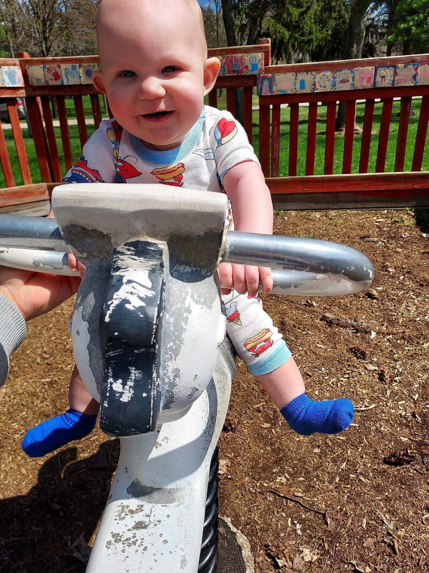 Weston is registered to the contest to win money with this photo: baby, baby_toddler_clothing, child, city, fun, grass, happy, leisure, outdoor_play_equipment, people_in_nature, person, personal_protective_equipment, play, playground, recreation, sitting, smile, soil, toddler, tree