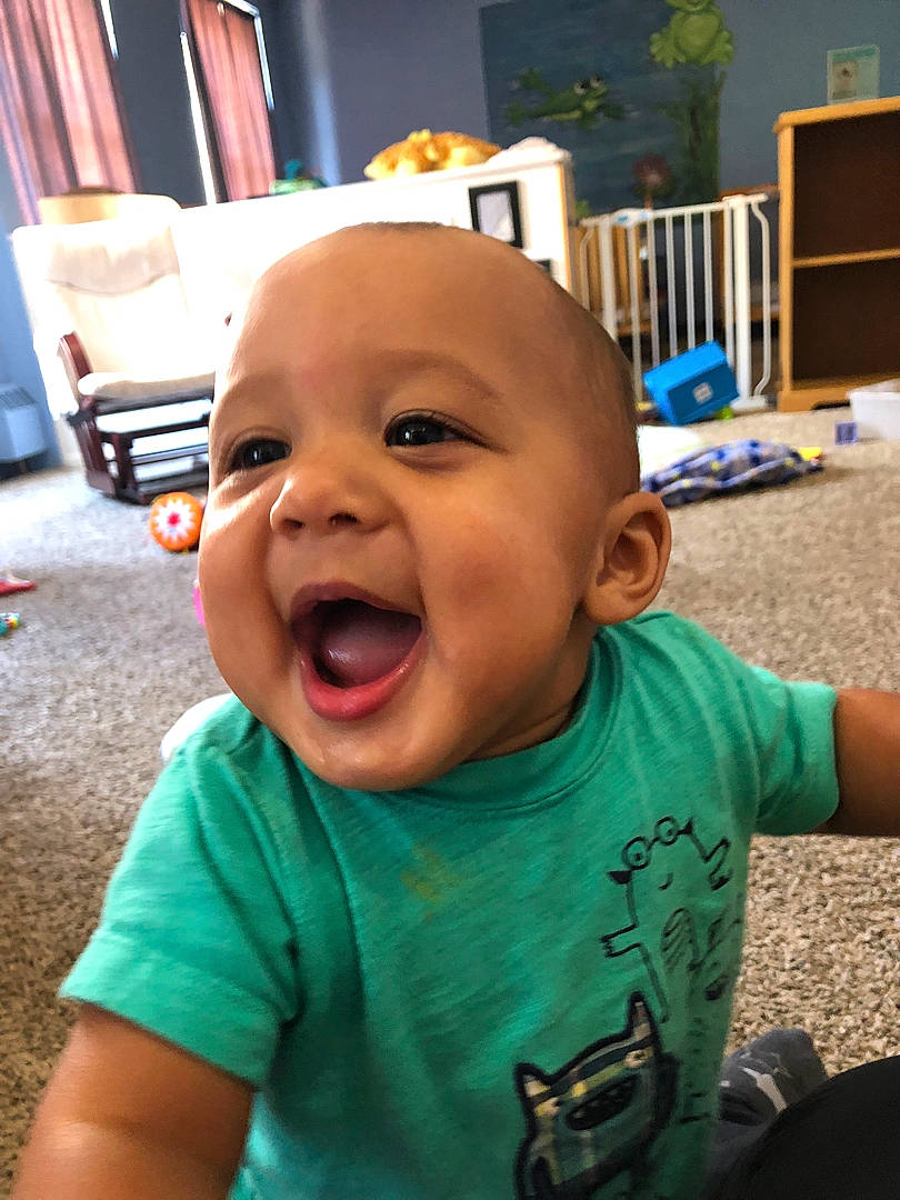 Isaiah joined the competition — help win amazing prizes! baby, baby_laughing, baby_toddler_clothing, camera, cheek, child, chin, clothing, cool, eye, fun, grass, happy, mouth, nose, person, sitting, sleeve, smile, t_shirt