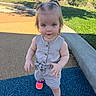 toddler, child, girl, standing, portrait, pigtails, smiling, playground, outdoor, sunny, romper, overalls, buttons, neon_shoes, sneakers, suburban, sidewalk, grass, residential, daylight