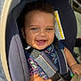 Amari is registered to the contest to win money with this photo: baby, blue_shirt, car_seat, child, close_up, curly_hair, cute, expression, hand, happy, indoor, infant, person, portrait, safety_harness, seat, seat_belt, skin, smile, sunlight