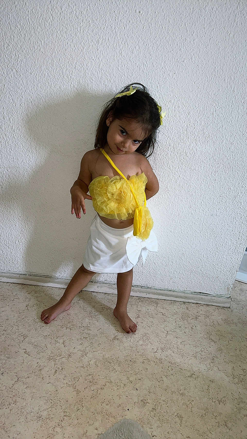 Layana participe au concours pour gagner de l'argent avec cette photo : child, girl, posing, yellow_top, white_skirt, barefoot, indoor, floor, wall, shadow, hair_bow, fashion, playful, attitude, smile, standing, person, cute, portrait, casual