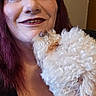 woman, dog, pet, smile, affection, indoor, curly_hair, red_hair, white_dog, closeup, friendship, love, portrait, happy, face, human, animal, cute, cozy, hair