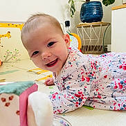 Charlie participe au concours pour gagner de l'argent avec cette photo : baby, child, smiling, play_mat, floral_clothing, indoor, toy, giraffe_illustration, face, happy, crawling, person, head, home_decor, plant, pot, floor, cute, infant, bright