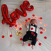 Tiago a rejoint le concours — aidez-le/la à gagner de superbes lots ! baby, infant, tuxedo_onesie, red_balloons, love, rose_petals, fairy_lights, white_sheet, milestone_marker, 1_month, cute, portrait, celebration, lying_down, newborn, baby_clothes, decor, holiday, lighting, baby_boy
