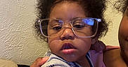 Malakai joined the competition — help win amazing prizes! adult, baby, child, closeup, clothing, couch, curly_hair, expression, face, glasses, hand, holding, indoor, light, person, portrait, texture, toddler, wall, wearing