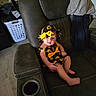 baby, child, hat, sunflower, outfit, recliner, chair, clothing, home_interior, furniture, floor, laundry_basket, curious, smile, barefoot, sitting, infant, indoor, person, cute