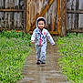toddler, child, hoodie, jacket, walking, pathway, wet, outdoor, garden, greenery, wooden_fence, smile, shoes, plants, nature, young_child, casual_clothing, daylight, cute, happy