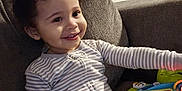 Legend is registered to the contest to win money with this photo: toddler, child, striped_pajamas, smiling, indoor, couch, toy, educational_toy, letters, animals, playful, happy, curly_hair, person, furniture, reaching, sitting, home, infant, cute