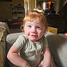 toddler, child, red_hair, bow, smile, indoor, living_room, couch, furniture, television, curly_hair, person, cute, young_child, casual_clothing, home, seated, portrait, happy, baby