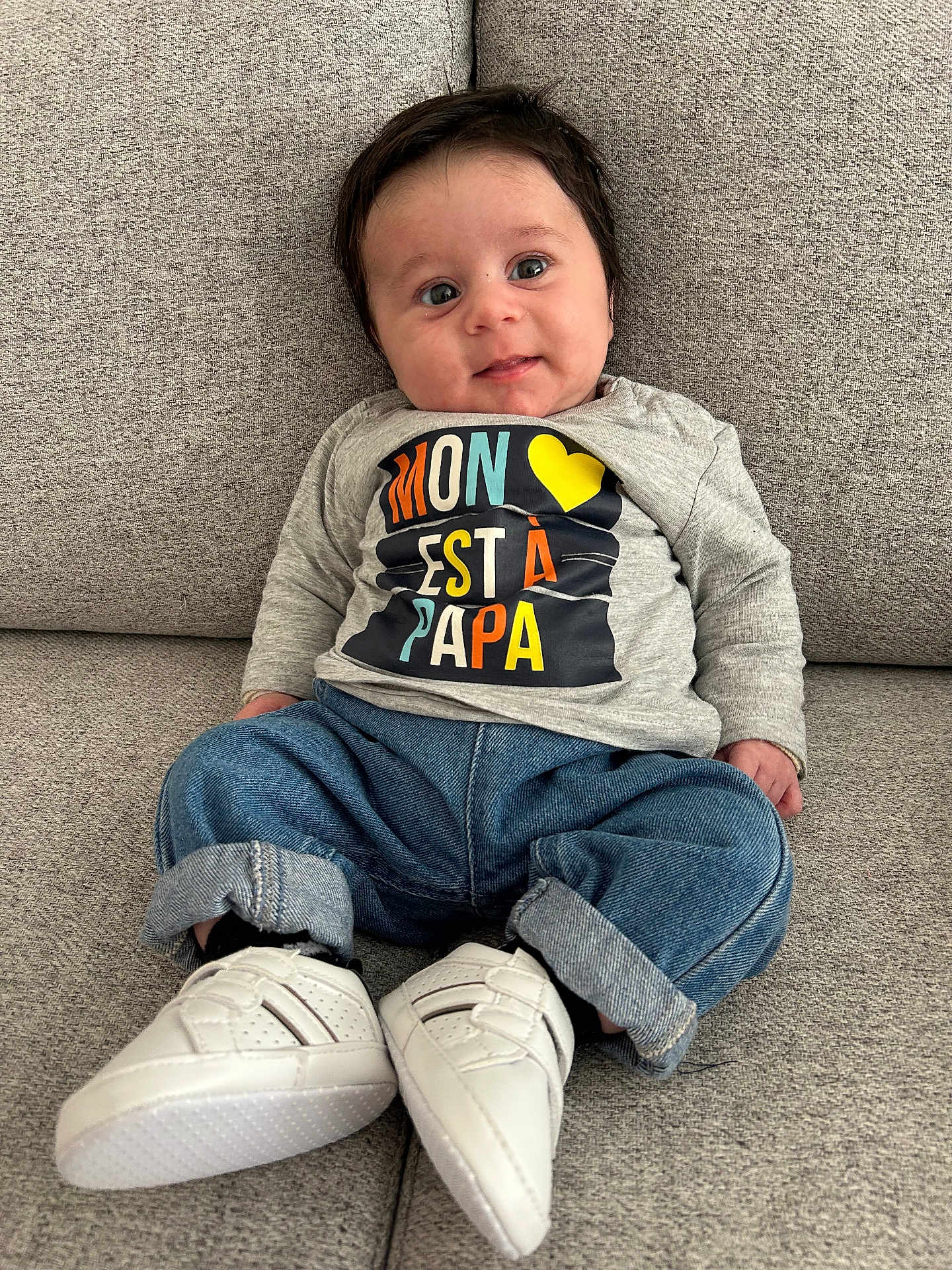 Aylan a rejoint le concours — aidez-le/la à gagner de superbes lots ! baby, infant, child, smiling, face, eyes, shirt, jeans, sneakers, footwear, couch, seated, casual_clothing, indoor, textile, portrait, cute, young, comfortable, colorful_text