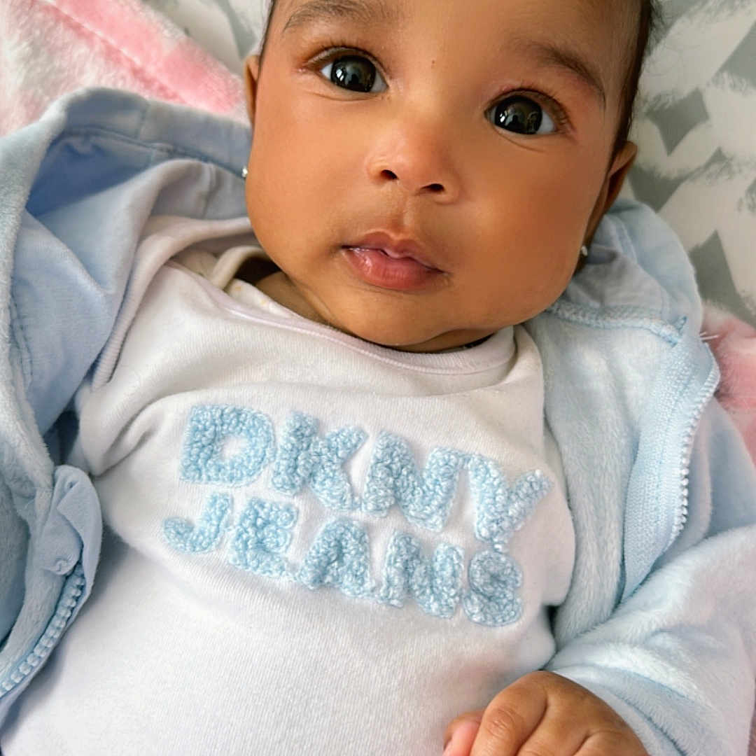 Ariana joined the competition — help win amazing prizes! baby, blanket, blue, child, closeup, clothing, cute, expression, eyes, face, hand, indoor, infant, jacket, pink, portrait, skin, soft_texture, white, young