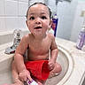 Zaylen joined the competition — help win amazing prizes! baby, child, bath_time, bathroom, sink, water, wet, sitting, red_cup, faucet, soap_bottle, infant, portrait, face, wide_eyes, curly_hair, smiling, indoors, hygiene, playful