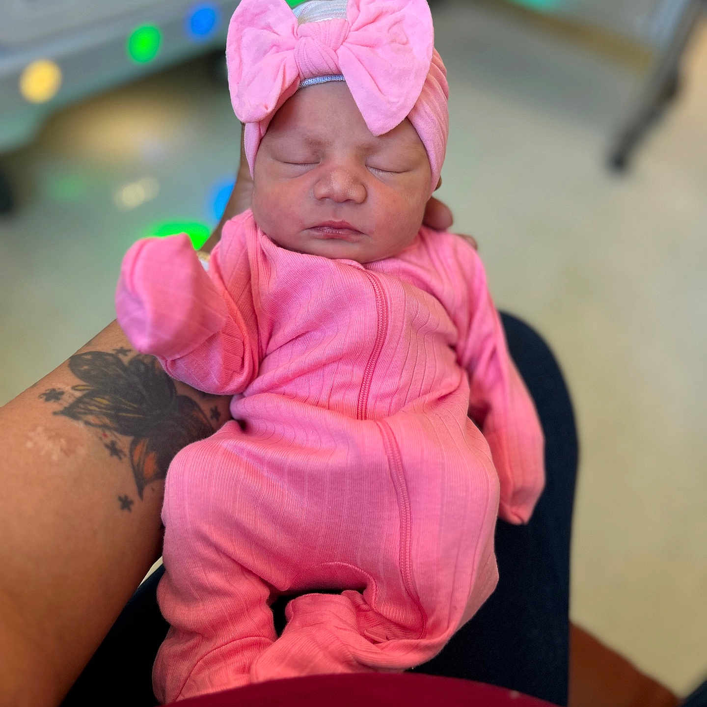 Amoura is registered to the contest to win money with this photo: newborn, baby, pink_outfit, headband, bow, sleeping, tattoo, arm, person, infant, indoor, closeup, soft_lighting, caring, holding, portrait, cute, peaceful, child, newborn_clothing