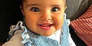 Amara a rejoint le concours — aidez-le/la à gagner de superbes lots ! baby, child, smiling, happy, pigtails, blue_vest, white_shirt, couch, indoor, portrait, person, cute, infant, seated, closeup, young_child, human, cozy, soft_texture, cheerful