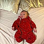 baby, infant, red_outfit, white_socks, bed, pillow, fabric, clothing, person, face, skin, newborn, lying_down, cute, small, cozy, soft, indoors, portrait, expression