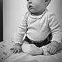 baby, infant, child, sitting, portrait, black_and_white, cute, expression, eyes, hands, socks, onesie, mattress, bed, pattern, nursery, shelf, wall, soft_lighting, closeup