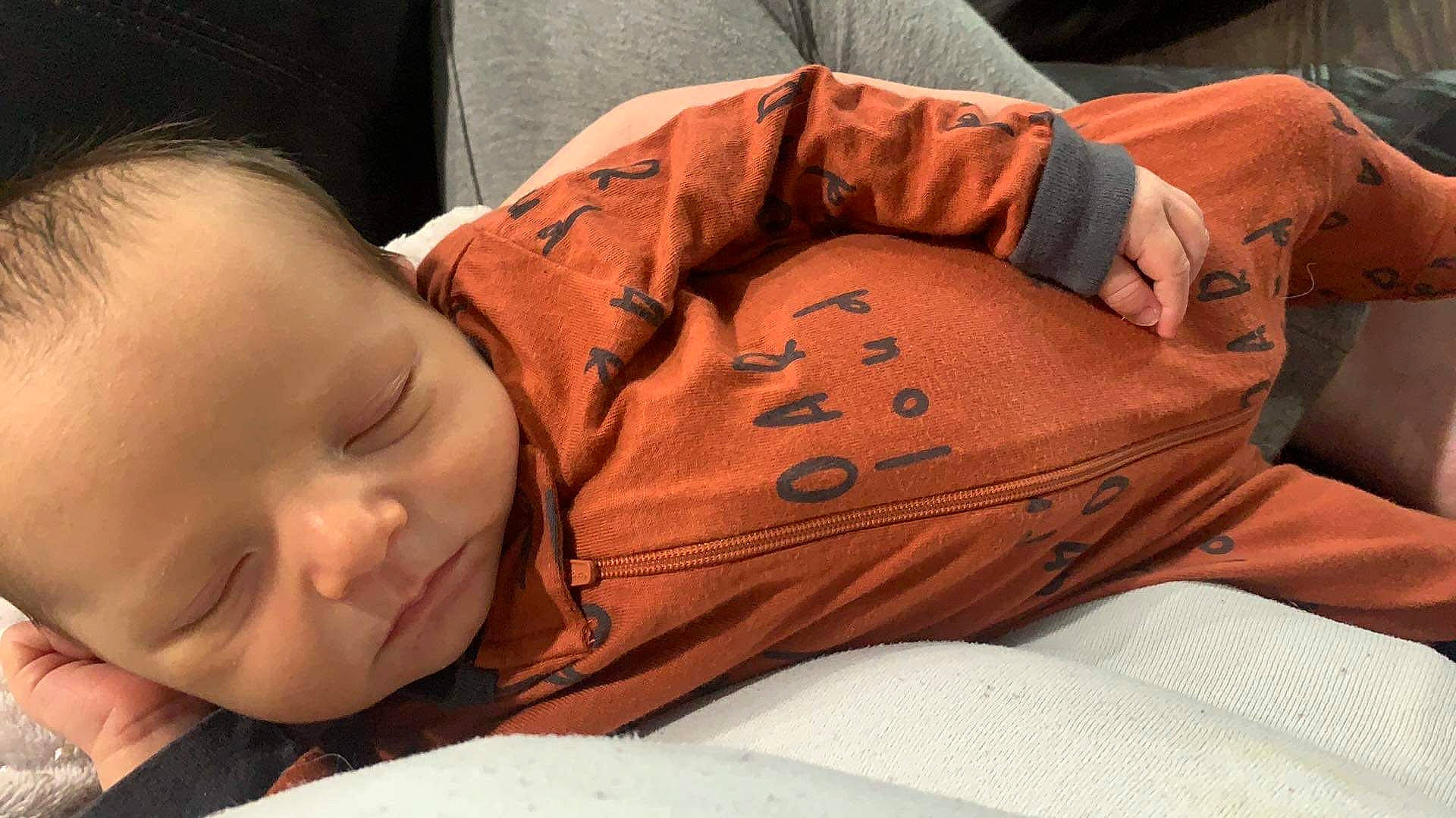 Colt is registered to the contest to win money with this photo: arm, baby, baby_toddler_clothing, cheek, comfort, elbow, facial_expression, finger, glasses, grass, hand, head, human_body, mouth, muscle, nose, orange, person, skin, thigh