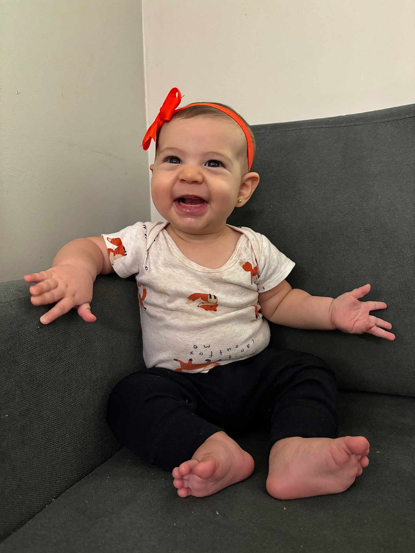 Martina joined the competition — help win amazing prizes! baby, child, smiling, happy, headband, orange, shirt, fox_pattern, couch, sitting, barefoot, arm_spread, indoor, furniture, cute, infant, portrait, person, expression, comfortable