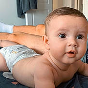 Maylone a rejoint le concours — aidez-le/la à gagner de superbes lots ! adult, arm, baby, bed, blanket, clothing, curious, diaper, eyes, face, furniture, hair, home, indoor, infant, lying_down, mouth, person, room, skin