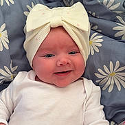 Myla is registered to the contest to win money with this photo: baby, infant, smiling, face, headband, bow, white_clothing, blanket, daisy_pattern, blue_blanket, cute, happy, child, newborn, lying_down, portrait, soft_texture, cozy, closeup, indoors