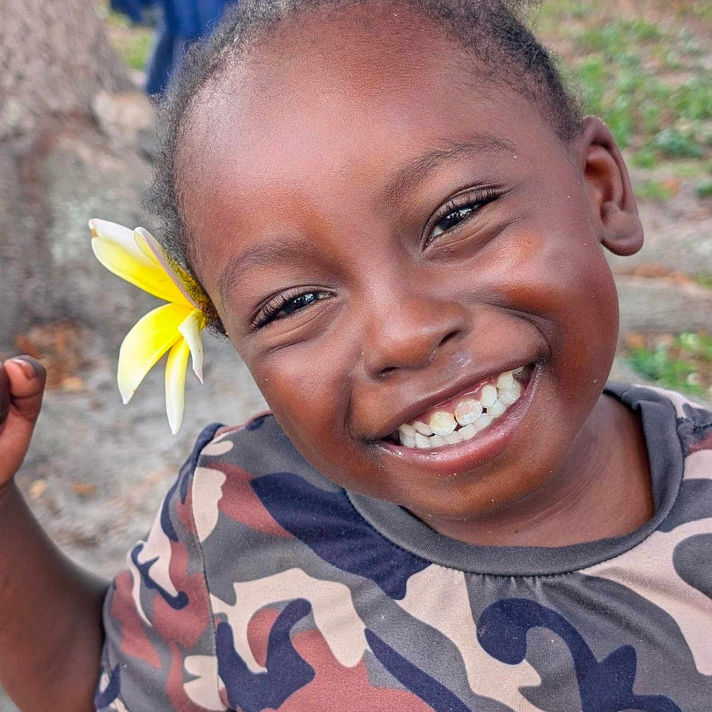 Lee Collins Jr is registered to the contest to win money with this photo: child, smiling, flower, outdoor, tree, grass, camouflage_clothing, face, happy, person, portrait, nature, young, joyful, casual_clothing, closeup, skin, hair, toddler, background_blur