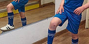 Haroun a rejoint le concours — aidez-le/la à gagner de superbes lots ! child, boy, soccer_ball, mirror, reflection, sportswear, blue_clothing, indoor, wooden_floor, stairs, socks, shoes, shorts, tshirt, sport, pose, home, casual, curly_hair, young