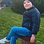 Haroun a rejoint le concours — aidez-le/la à gagner de superbes lots ! child, boy, smile, beanie, jacket, jeans, sneakers, sitting, outdoor, grass, park, metal_post, casual, portrait, happy, nature, daylight, young, person, relaxing