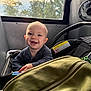 baby, smile, child, car_seat, window, trees, sky, bag, indoor, seat, clothing, happy, person, face, infant, transportation, sunlight, hand, zipper, fan