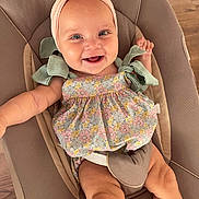 Valentina participe au concours pour gagner de l'argent avec cette photo : baby, child, smiling, headband, bow, floral_dress, blue_eyes, baby_chair, cushion, wooden_floor, happy, infant, sitting, cute, indoors, portrait, skin, person, clothing, closeup