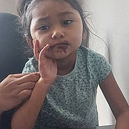 Lily joined the competition — help win amazing prizes! child, girl, chocolate, messy_face, table, foil, hand, clothing, indoor, portrait, casual, brown_hair, expression, seated, resting_face, adult_hand, knitted_cloth, young, curly_hair, contemplative