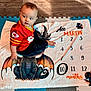 Ace joined the competition — help win amazing prizes! baby, child, milestone_blanket, dragon, red_jersey, kansas_city_chiefs, floor_mat, wooden_floor, sitting, indoor, curious, clothing, numbers, months, play_mat, portrait, cute, infant, looking_away, young_child
