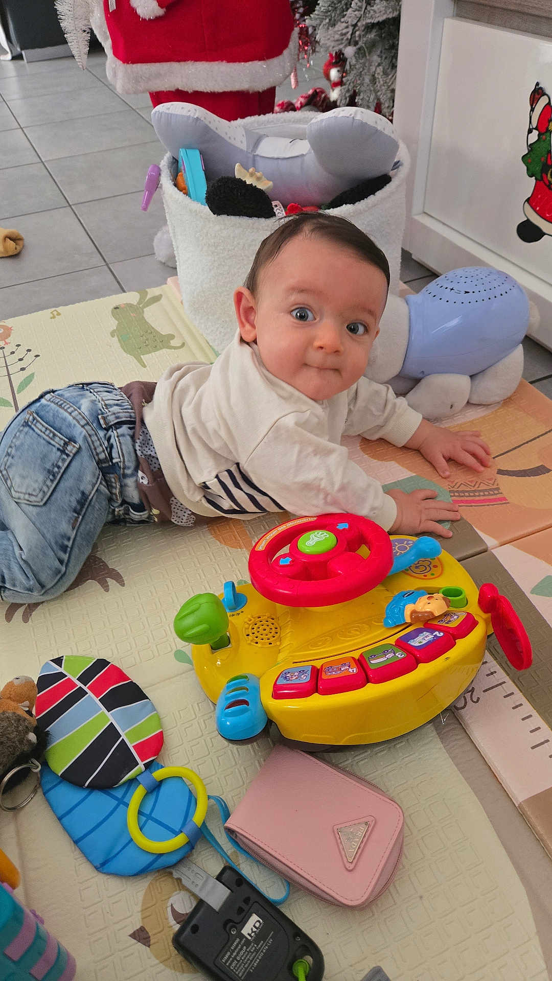 Julian a rejoint le concours — aidez-le/la à gagner de superbes lots ! baby, child, indoor, toy, play_mat, denim, sweater, floor, colorful, musical_toy, wallet, curious, wide_eyes, plastic_toy, soft_toy, tile_floor, festive_decor, crawling, infant, person