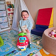 Julian a rejoint le concours — aidez-le/la à gagner de superbes lots ! ball_pit, balls, bear_print, carpet, child, colorful, foam_block, furniture, happy, indoor, play, play_mat, playroom, portrait, smiling, steering_wheel, storage_drawer, teepee, toddler, toy_car