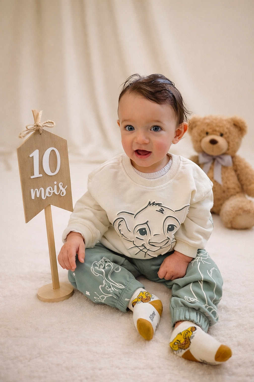 Julian a rejoint le concours — aidez-le/la à gagner de superbes lots ! age_marker, baby, child, cozy, cute, happy, indoor, lion_king_clothing, milestone, playful, portrait, sitting, smiling, socks, soft_carpet, studio, teddy_bear, toy, wooden_sign, young_child