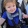 toddler, child, smile, stroller, blue_shirt, shorts, outdoor, sunlight, happy, seatbelt, baby, cute, person, daylight, casual_clothing, young_child, seat, playful, young_baby, cheerful