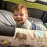 baby, crib, blanket, smile, face, dimples, curly_hair, bed, sleepwear, child, infant, happy, indoors, soft_lighting, person, cute, expression, cozy, playful, elephant_pattern