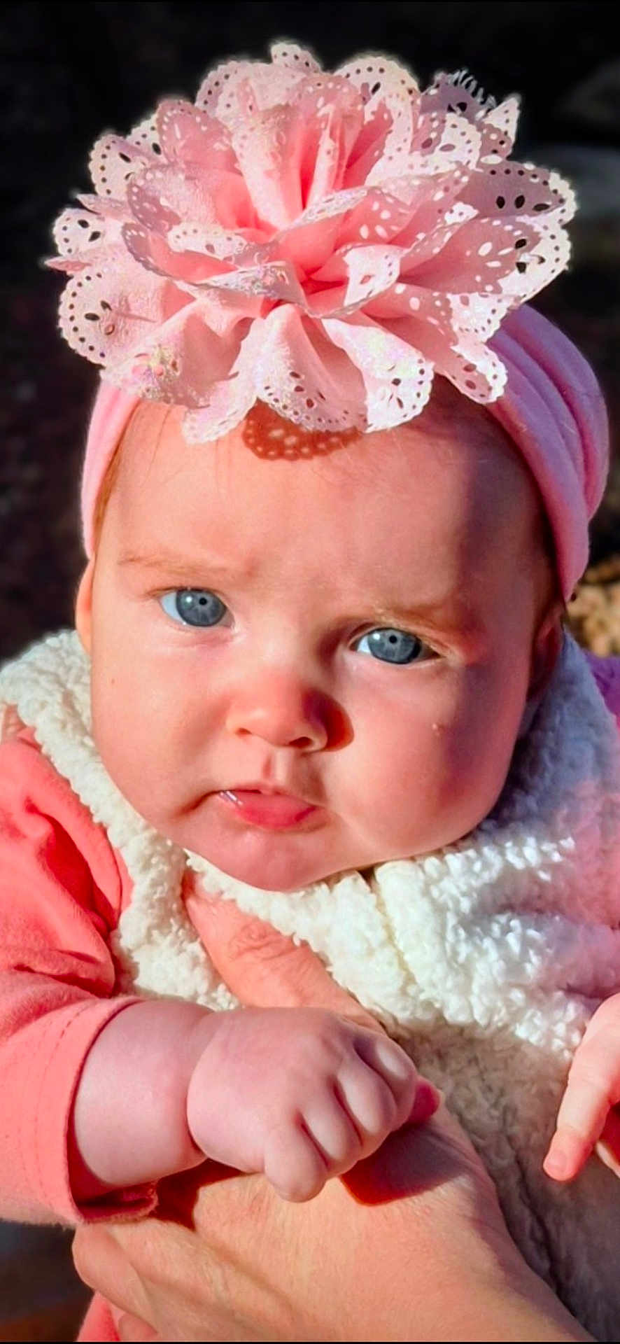 Serene joined the competition — help win amazing prizes! baby, child, blue_eyes, headband, flower, pink, fleece, vest, hand, skin, closeup, portrait, cute, infant, outdoor, person, natural_light, expression, young, holding