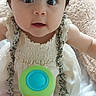 baby, child, infant, sitting, portrait, wide_eyes, looking_at_camera, open_mouth, smiling, frilly_dress, white_clothing, toy, green_toy, blue_toy, blanket, indoor, home, close_up, face, photography