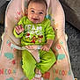 baby, smiling, green_clothing, baby_chair, unicorn_pattern, pastel_colors, happy, infant, indoor, cute, child, socks, plush_chair, face, seated, cozy, grinch_theme, colorful, soft_texture, adorable