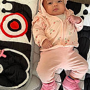 Eliana is registered to the contest to win money with this photo: baby, infant, pink_clothing, hoodie, booties, quilt, patterned_blanket, cute, lying_down, indoor, soft_toys, comfortable, child, newborn, cozy, casual_wear, portrait, person, small_hands, expression