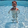 child, boy, pool, water, swimming, summer, outdoor, happy, wet_hair, sunlight, reflection, tile, grass, playful, smile, recreation, daytime, water_surface, kid, fun