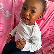 Infinity is registered to the contest to win money with this photo: toddler, child, smiling, white_shirt, dark_pants, pink_blanket, bow, earrings, indoor, happy, cute, portrait, sitting, curly_hair, baby, person, face, skin, small_teeth, cozy