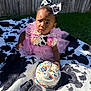 toddler, child, birthday_cake, pink_tutu, flower_accessories, cow_pattern, bow, blanket, outdoor, grass, fence, celebration, sprinkles, candle, cake, happy, cute, portrait, sitting, sunlight