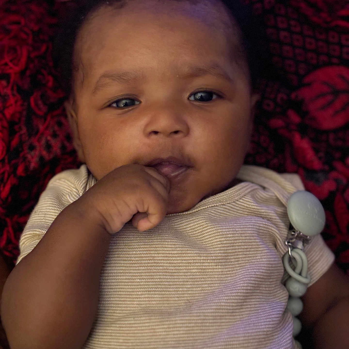 Drasyn is registered to the contest to win money with this photo: baby, baby_garment, blanket, child, closeup, clothing, cute, expression, face, hand, indoors, infant, lying_down, pacifier_clip, patterned_blanket, person, portrait, skin, striped_shirt, young