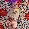 Brian joined the competition — help win amazing prizes! baby, child, infant, valentines_day, heart, blanket, portrait, lying_down, smiling, happy, face, clothing, striped_pants, long_sleeves, headband, lights, red, white, kisses, indoor