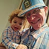child, toddler, adult, selfie, portrait, smiling, happy, family, indoor, curtains, sunlight, hat, glasses, plaid_shirt, baby, curly_hair, close_up, sitting, parent, wholesome