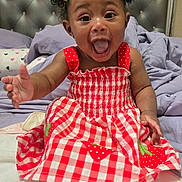 Jenesis joined the competition — help win amazing prizes! baby, child, smiling, happy, dress, red_dress, hair_bows, curly_hair, bed, bedding, pillow, tufted_headboard, indoor, cute, portrait, sitting, reaching_out, infant, person, cheerful
