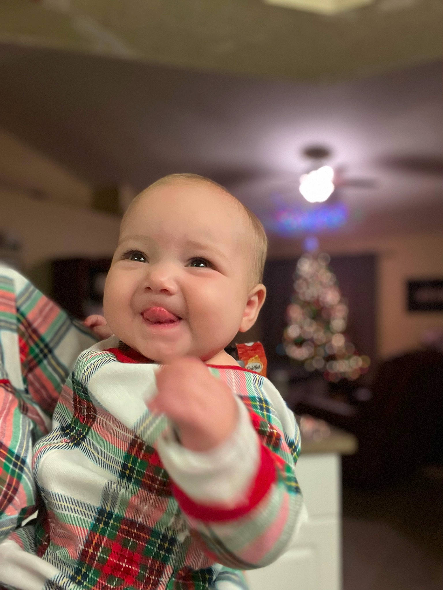 Kiara is registered to the contest to win money with this photo: baby, baby_toddler_clothing, carmine, cheek, child, christmas, christmas_tree, event, fun, happy, holiday, joy, pattern, person, plaid, room, sitting, sleeve, smile, tartan